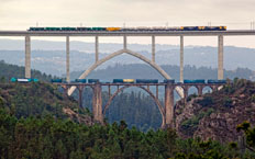 Vista frontal del nuevo puente en donde se puede apreciar en primer plano el puente antiguo. En la instantánea se aprecian trenes de mercancias cruzando por ambos puentes a la vez